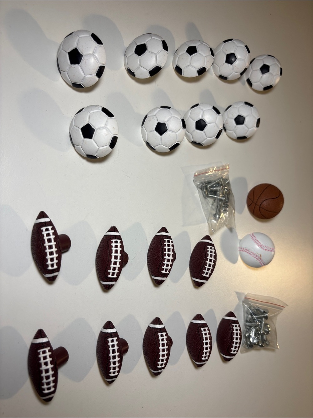 Sports drawer pulls and screws. 9 soccer balls, 9 footballs 1 baseball, 1 bball
